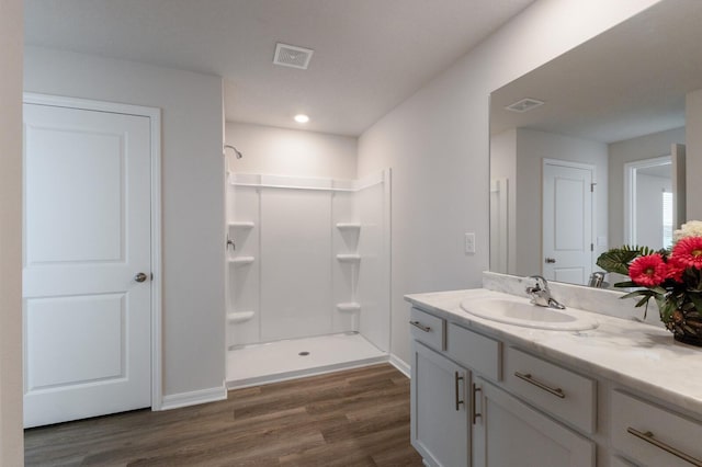 bathroom with hardwood / wood-style floors, vanity, and walk in shower