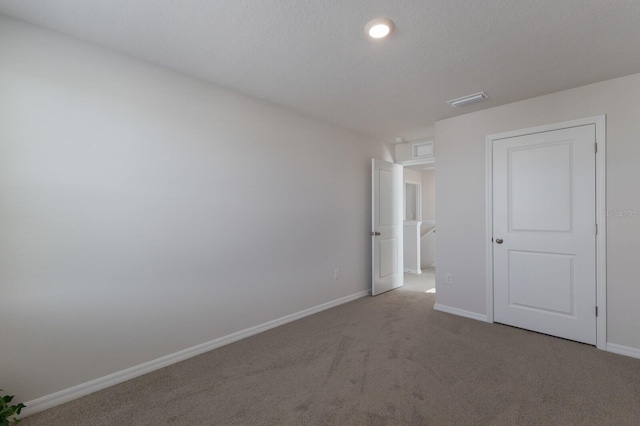 unfurnished bedroom featuring a textured ceiling and light colored carpet