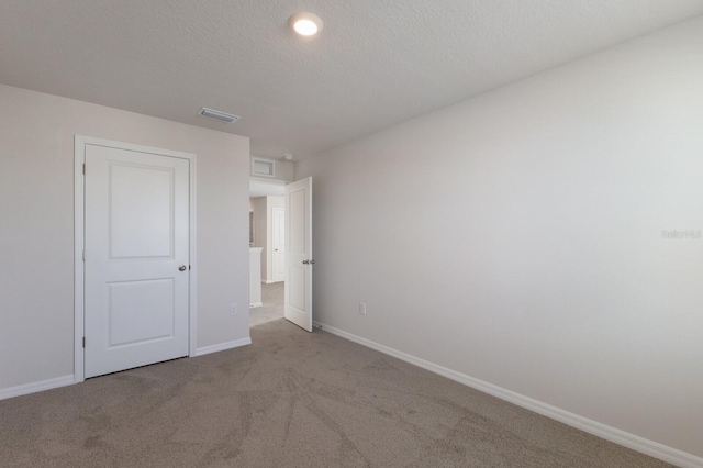 unfurnished bedroom featuring light carpet and a textured ceiling