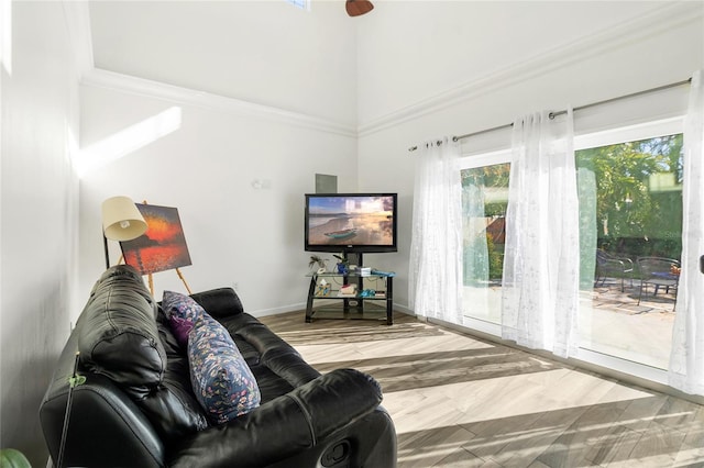 living room with wood-type flooring, a towering ceiling, and crown molding