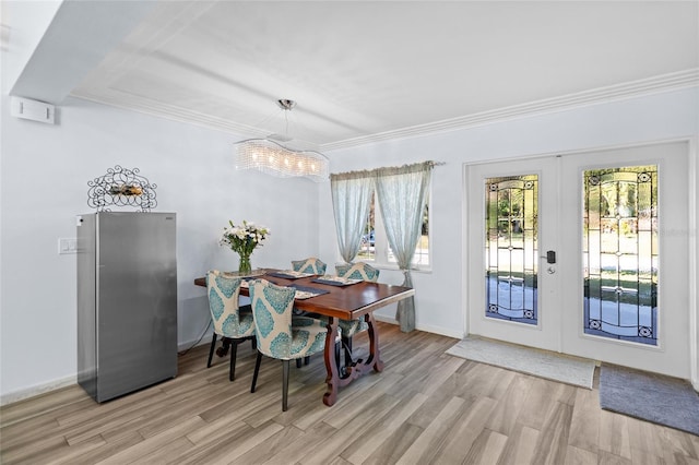 dining space featuring crown molding, french doors, light hardwood / wood-style floors, and a notable chandelier