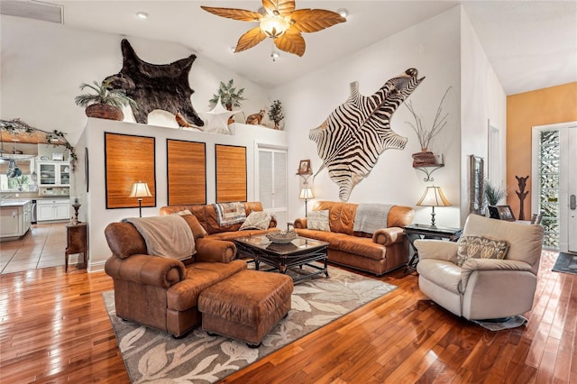 living room with ceiling fan, high vaulted ceiling, and light hardwood / wood-style floors