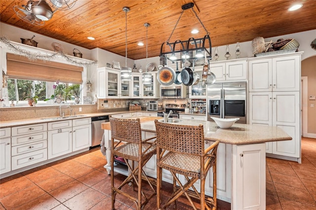 kitchen featuring wooden ceiling, stainless steel appliances, backsplash, a kitchen island with sink, and sink