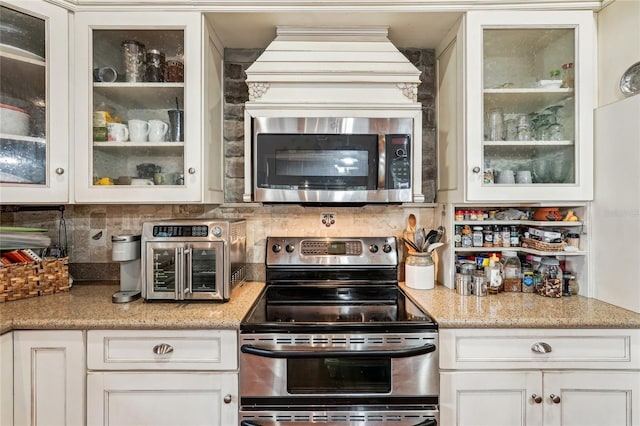 kitchen with tasteful backsplash, light stone counters, stainless steel appliances, and white cabinetry