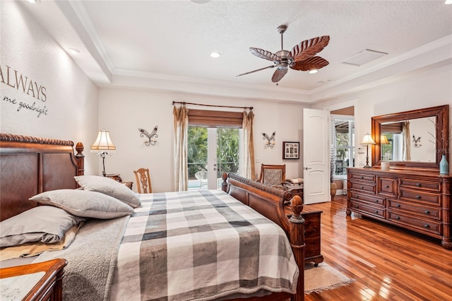 bedroom featuring a textured ceiling, access to exterior, hardwood / wood-style flooring, ceiling fan, and a tray ceiling