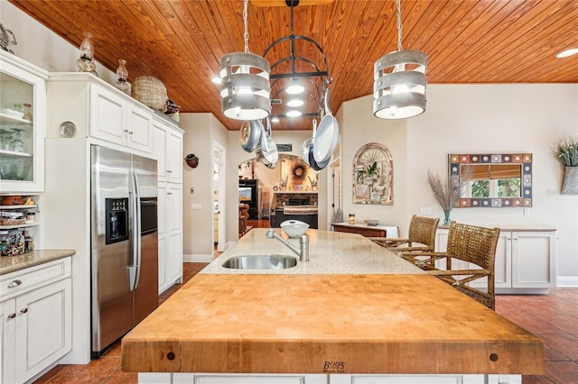 kitchen with white cabinetry, sink, stainless steel fridge, and decorative light fixtures