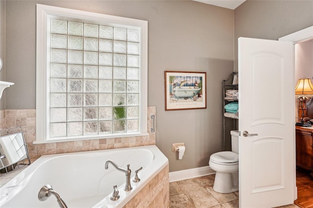 bathroom with toilet and tiled tub