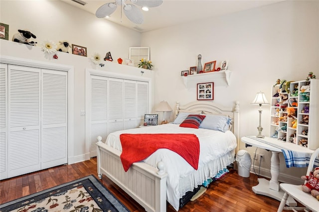 bedroom featuring dark wood-type flooring, ceiling fan, and multiple closets