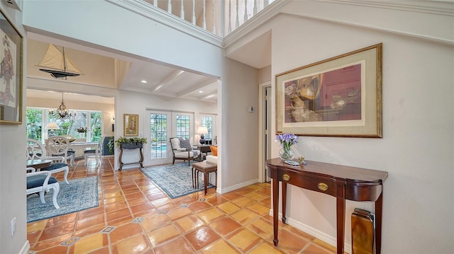 foyer entrance featuring beamed ceiling, plenty of natural light, light tile patterned floors, and french doors