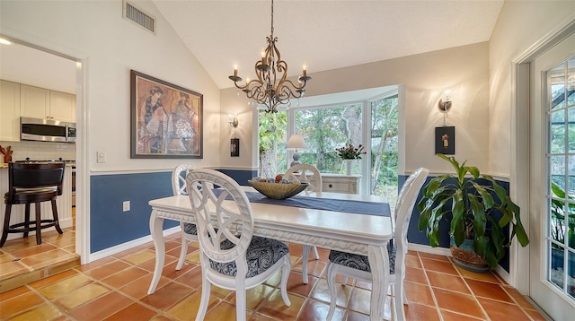 tiled dining area with a chandelier, vaulted ceiling, and a wealth of natural light