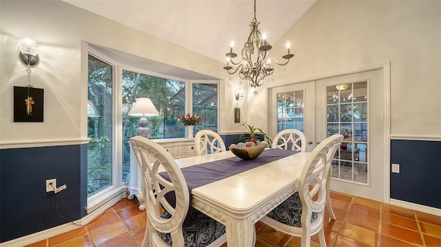 dining area with tile patterned floors, lofted ceiling, and an inviting chandelier