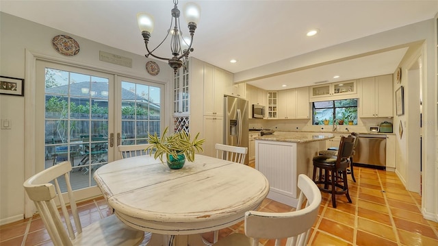 dining space with sink, light tile patterned floors, and a notable chandelier