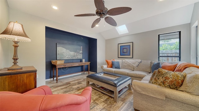 living room featuring hardwood / wood-style floors, ceiling fan, and lofted ceiling with skylight