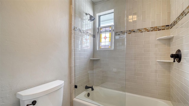 bathroom with tiled shower / bath combo and toilet