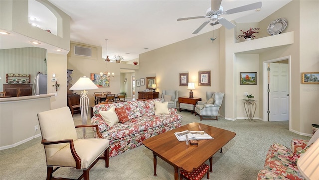 carpeted living room featuring ceiling fan with notable chandelier and high vaulted ceiling