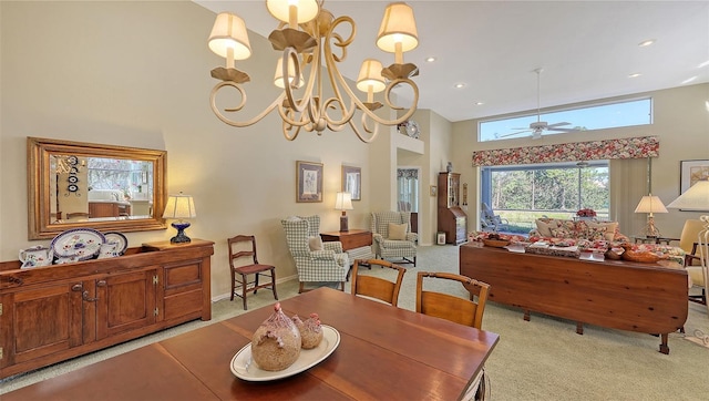 carpeted dining area featuring ceiling fan with notable chandelier and a high ceiling