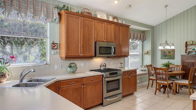 kitchen featuring decorative backsplash, appliances with stainless steel finishes, sink, decorative light fixtures, and an inviting chandelier