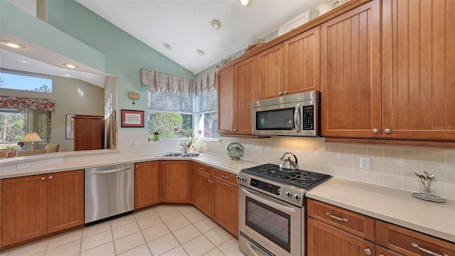 kitchen with decorative backsplash, light tile patterned floors, vaulted ceiling, and appliances with stainless steel finishes