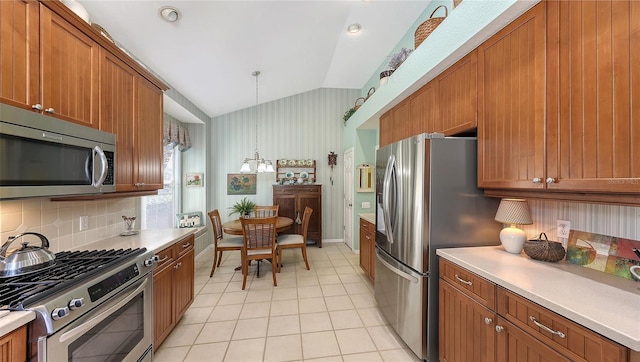 kitchen with pendant lighting, lofted ceiling, decorative backsplash, light tile patterned floors, and stainless steel appliances