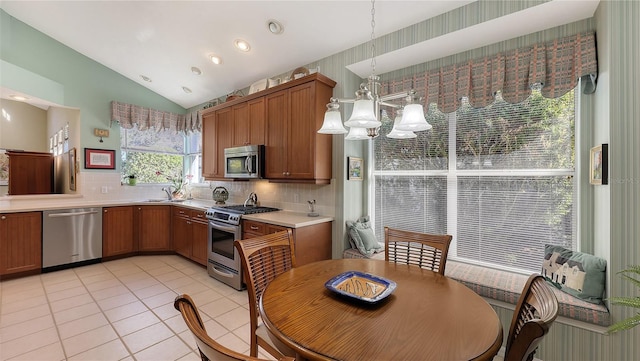 kitchen featuring lofted ceiling, decorative backsplash, decorative light fixtures, and appliances with stainless steel finishes