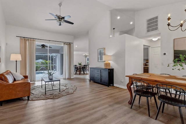 living room featuring hardwood / wood-style flooring, ceiling fan with notable chandelier, and a towering ceiling