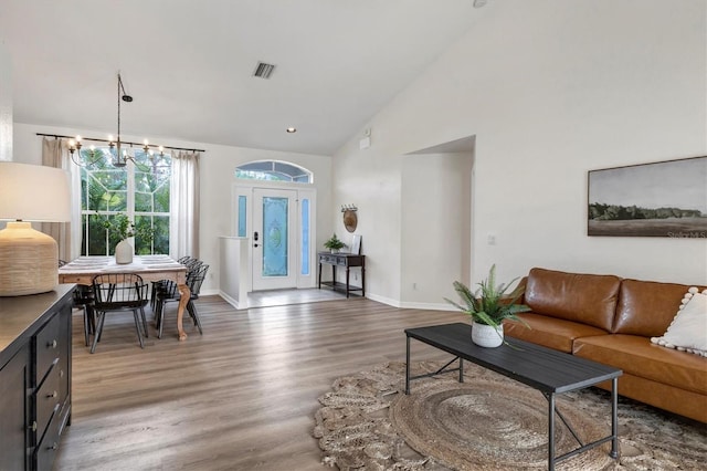 living room with dark hardwood / wood-style flooring, high vaulted ceiling, and an inviting chandelier