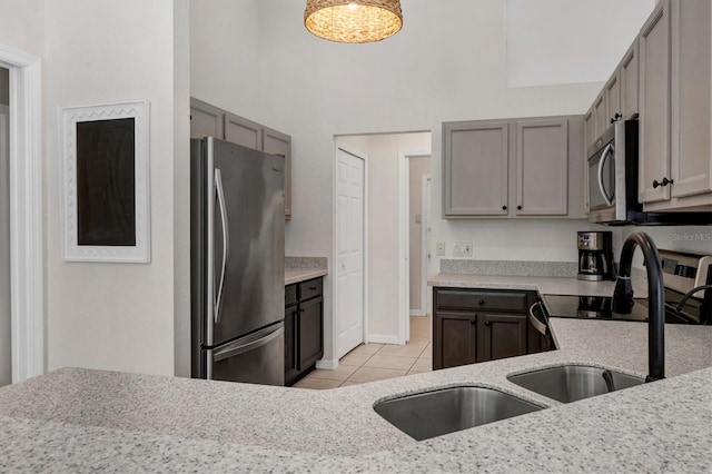 kitchen featuring light tile patterned floors, stainless steel appliances, gray cabinets, and light stone counters