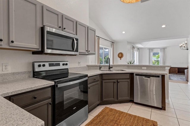 kitchen with lofted ceiling, an inviting chandelier, sink, light tile patterned floors, and appliances with stainless steel finishes