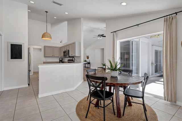 tiled dining space featuring ceiling fan and high vaulted ceiling