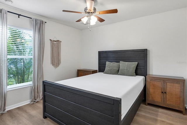 bedroom with multiple windows, light hardwood / wood-style floors, and ceiling fan