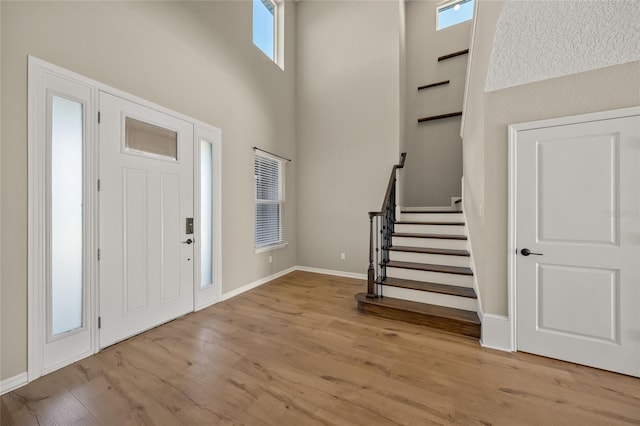 foyer entrance with light hardwood / wood-style floors and a high ceiling