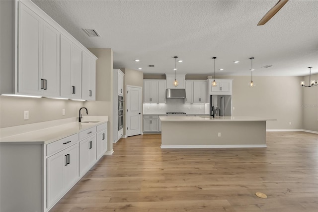 kitchen featuring decorative light fixtures, a kitchen island, sink, white cabinets, and high end fridge