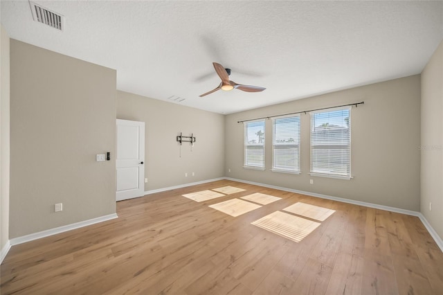 spare room with a textured ceiling, ceiling fan, and light hardwood / wood-style flooring