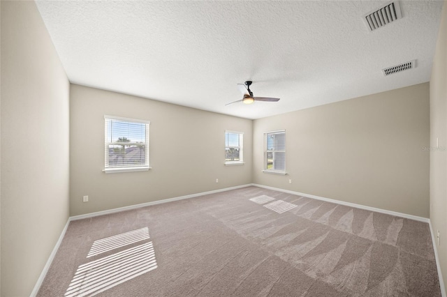 empty room featuring a textured ceiling, light colored carpet, and ceiling fan