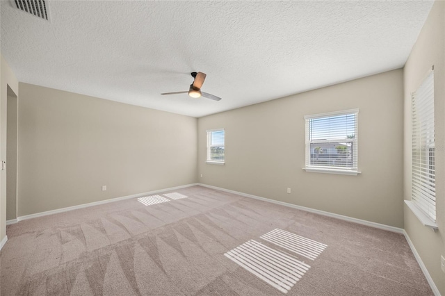 empty room featuring ceiling fan, a textured ceiling, and light colored carpet