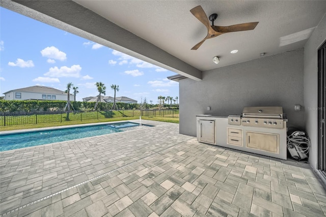 view of patio featuring ceiling fan, area for grilling, an outdoor kitchen, and a fenced in pool