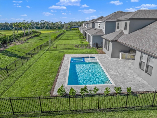 view of swimming pool with area for grilling, a rural view, a patio area, and a lawn