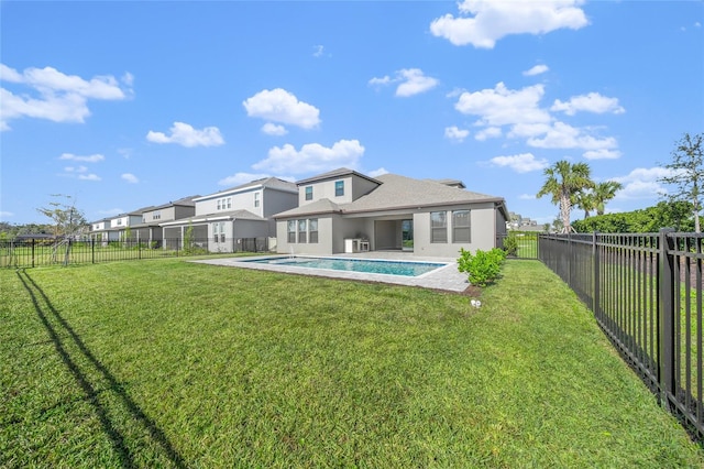 rear view of property with a patio, a lawn, and a fenced in pool