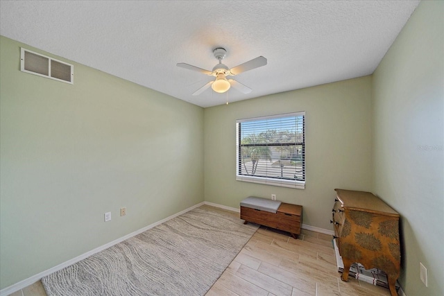 spare room featuring ceiling fan, light hardwood / wood-style flooring, and a textured ceiling