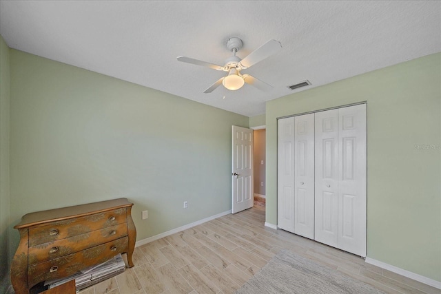 unfurnished bedroom featuring light hardwood / wood-style flooring, ceiling fan, and a closet