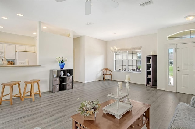 living room featuring ceiling fan with notable chandelier and hardwood / wood-style flooring