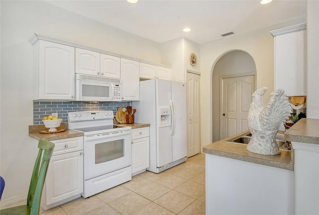 kitchen featuring decorative backsplash, light tile patterned floors, white cabinets, and white appliances