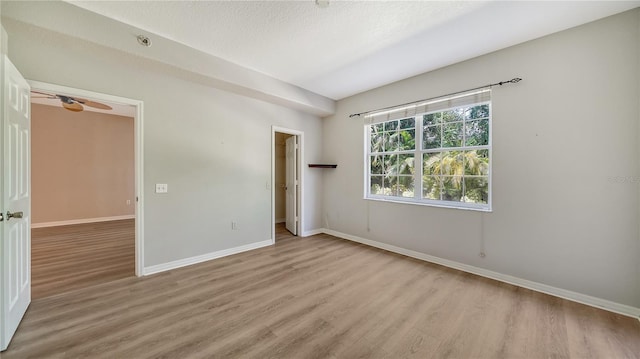 unfurnished room featuring ceiling fan, light wood-type flooring, and a textured ceiling