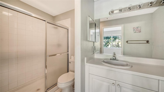 bathroom with a shower with door, vanity, and toilet