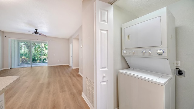 laundry room featuring a textured ceiling, light wood-type flooring, stacked washing maching and dryer, and ceiling fan