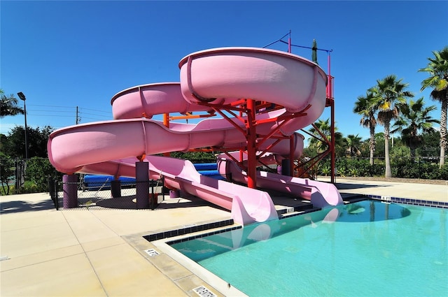 view of swimming pool featuring a playground, a patio, and a water slide