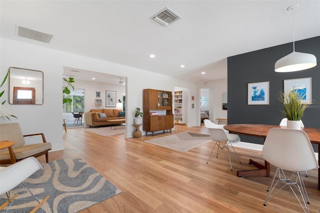 dining area with a textured ceiling and light hardwood / wood-style flooring