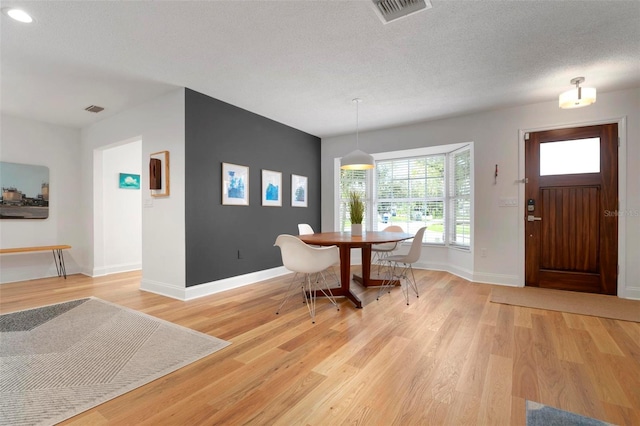 dining space with hardwood / wood-style floors and a textured ceiling