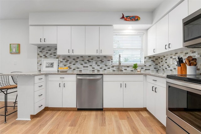 kitchen with light stone countertops, stainless steel appliances, white cabinetry, and tasteful backsplash