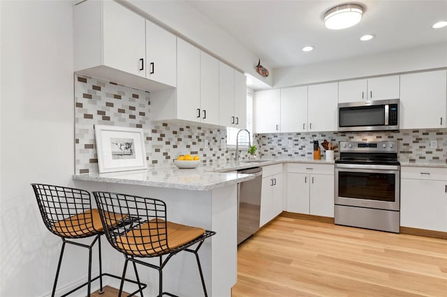 kitchen featuring a kitchen bar, white cabinetry, sink, and appliances with stainless steel finishes